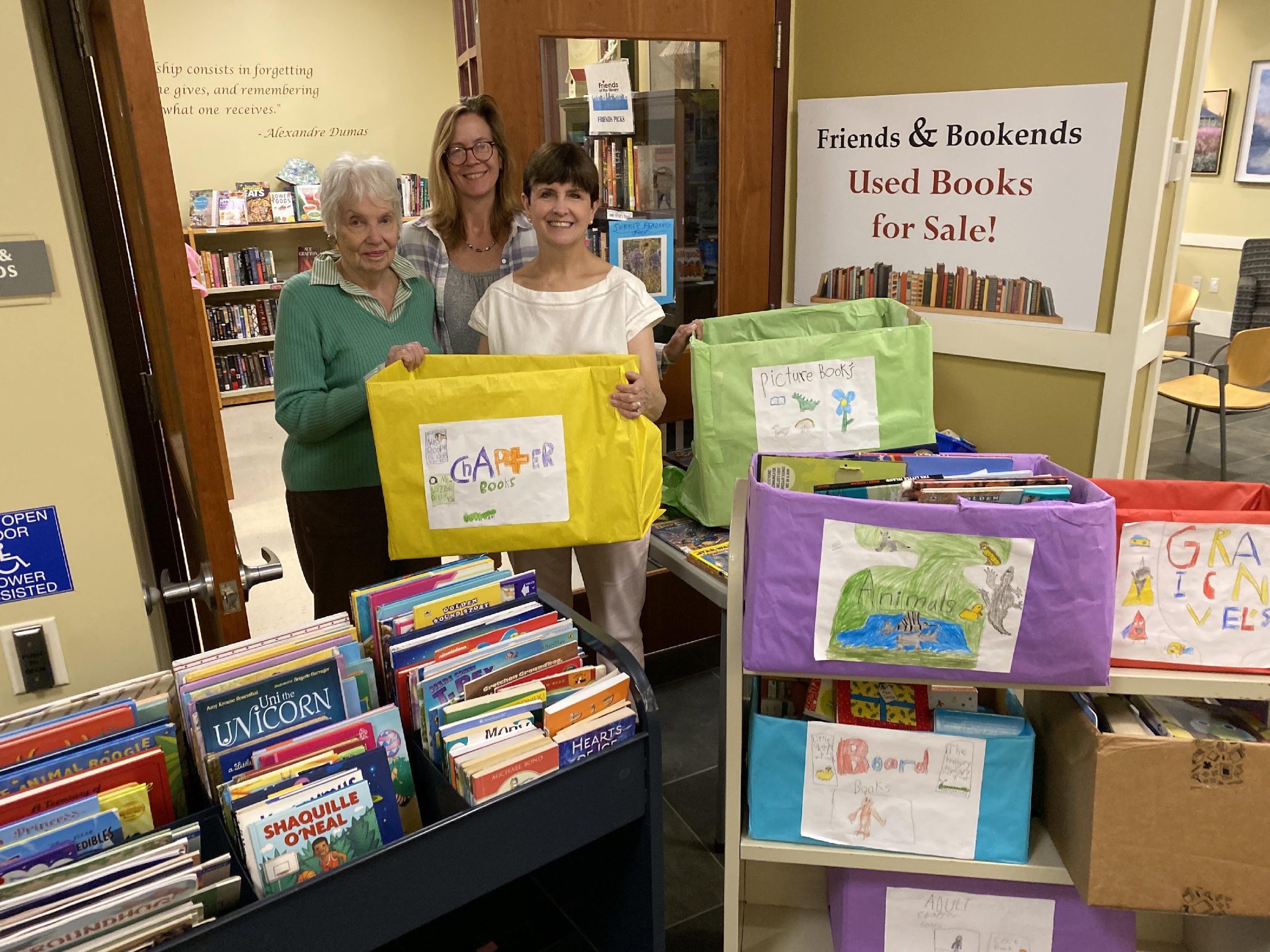 (from left) Friends of the Library volunteer Leslie Faulds, member of the circulation staff and liaison to the Friends of the Library Lauren Hoffman, and AWPL Director Lisa Laico stand amid books donated by PIE students from Sanfordville Elementary School.